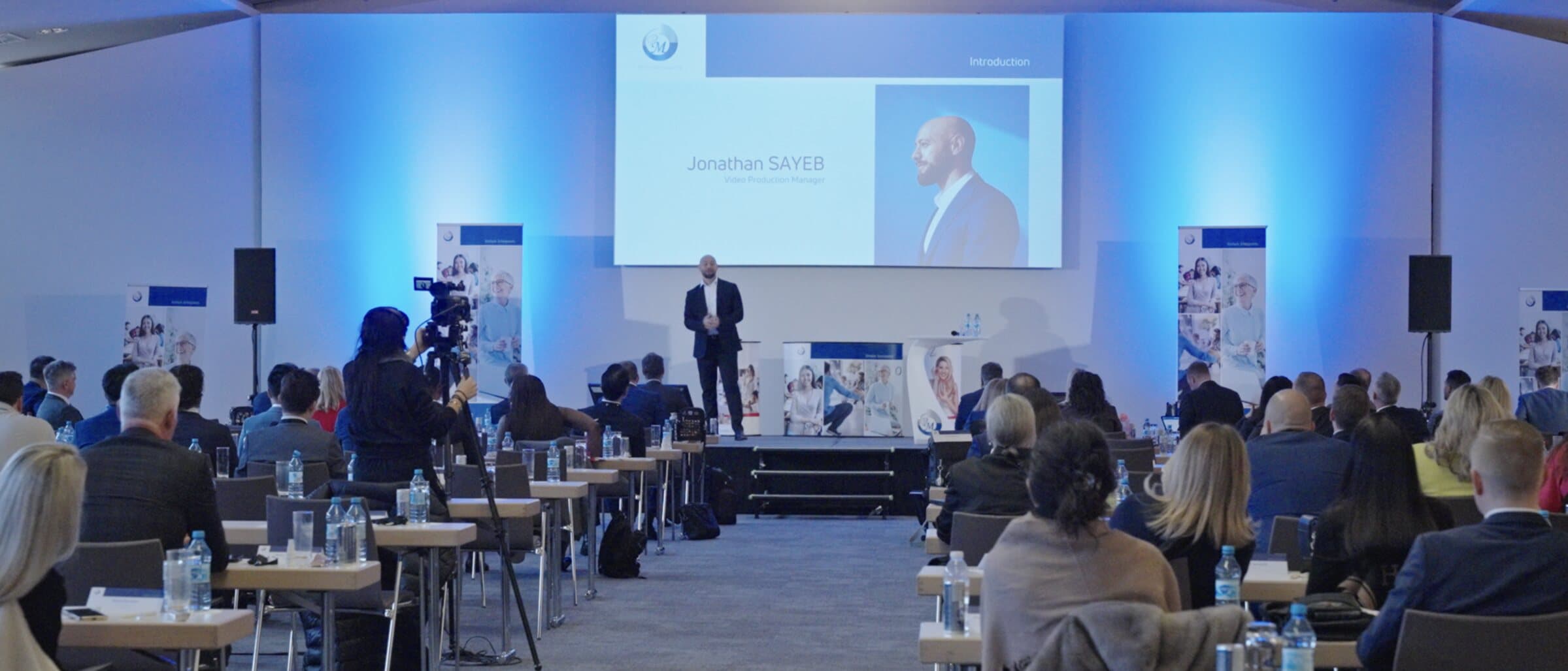 Jonathan Sayeb presenting AI projects to a large seated enterprise audience in Berlin.